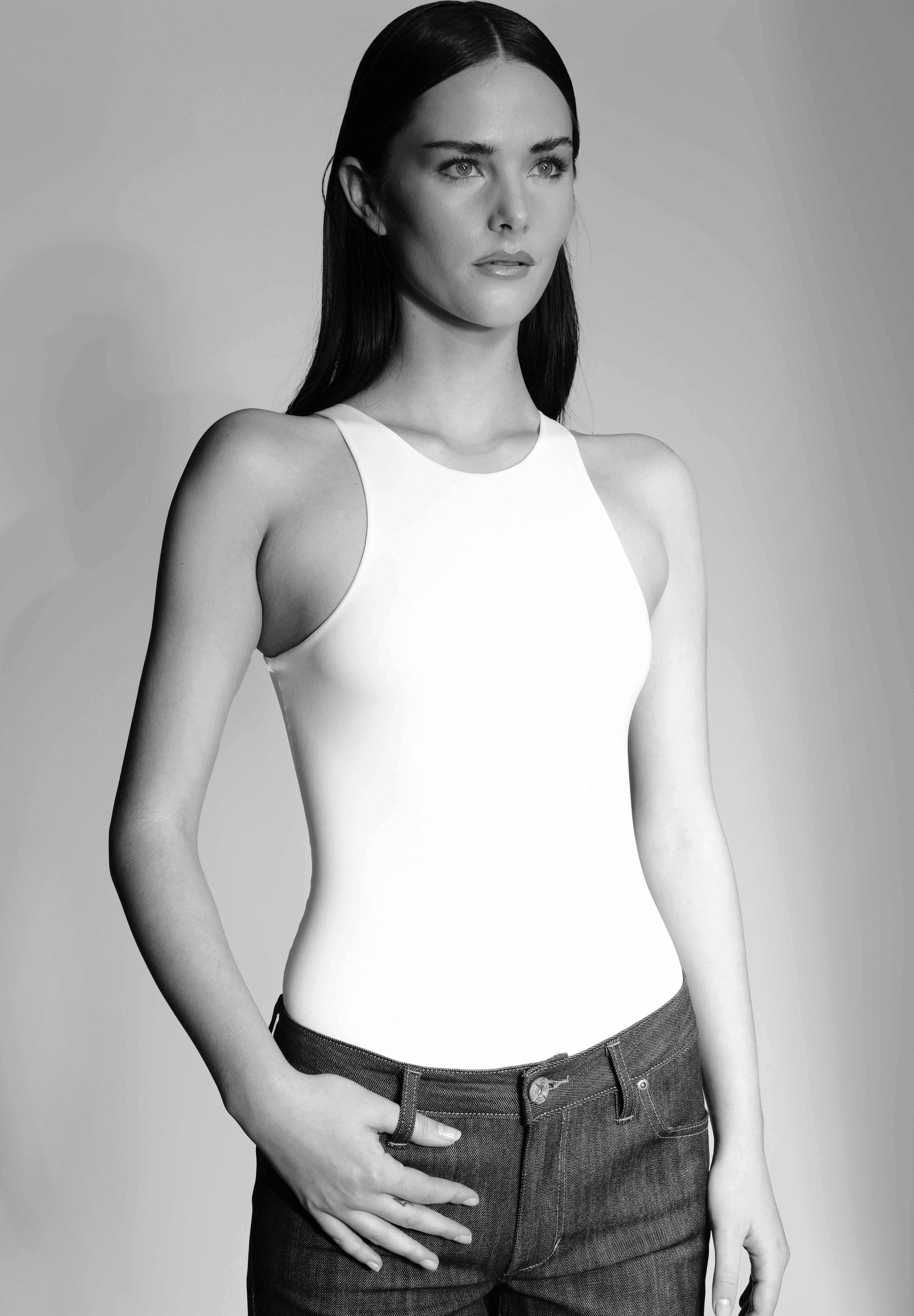 woman in a white bodysuit and raw denim jeans