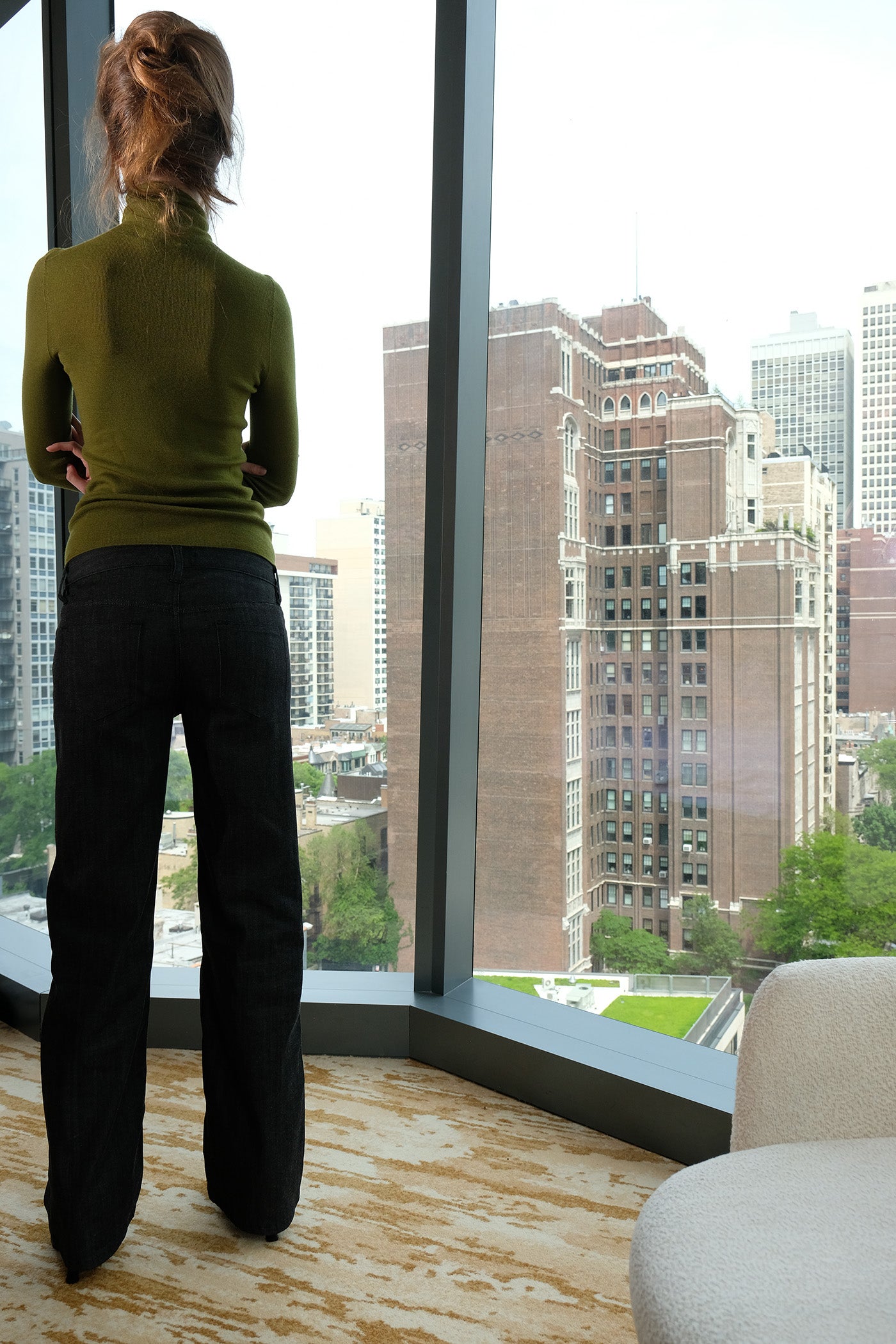Person standing by a large window with a cityscape view