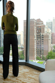 Person standing by a large window with a cityscape view
