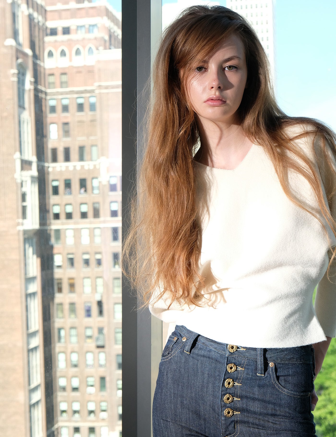 Woman standing in front of a glass window with cityscape background