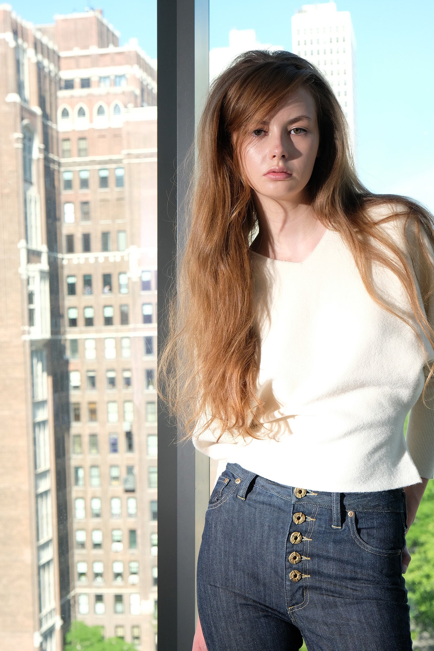 Woman standing in front of a glass window with cityscape background