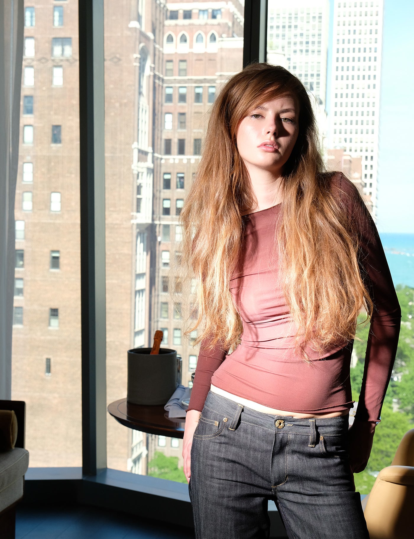 Woman standing in a room with large windows showing cityscape