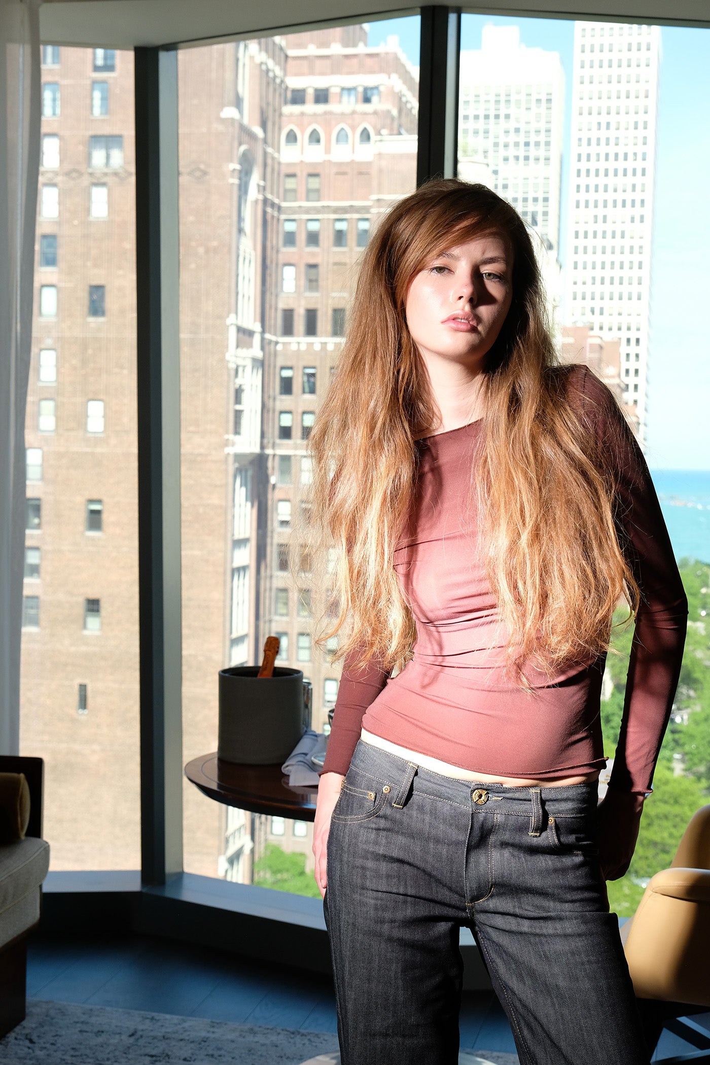 Woman standing in a room with large windows showing cityscape