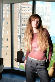 Woman standing in a room with large windows showing cityscape