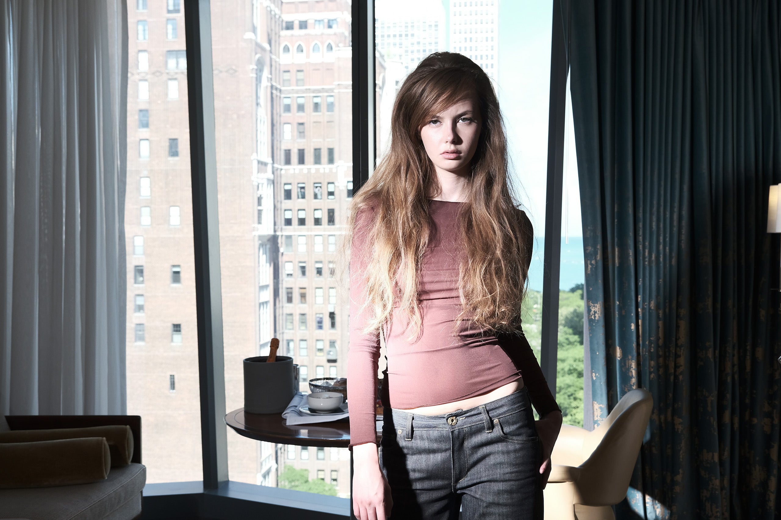 Woman standing in a room with large windows overlooking a cityscape