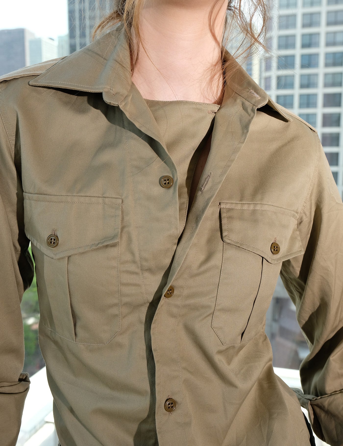 Person wearing a safari shirt with a cityscape background