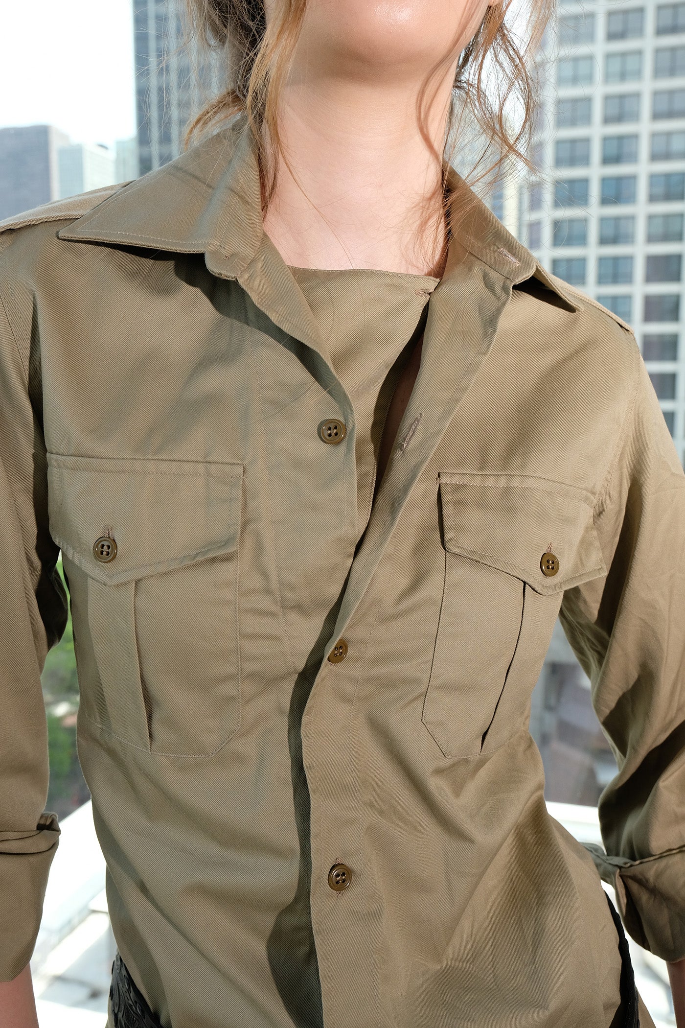 Person wearing a safari shirt with a cityscape background