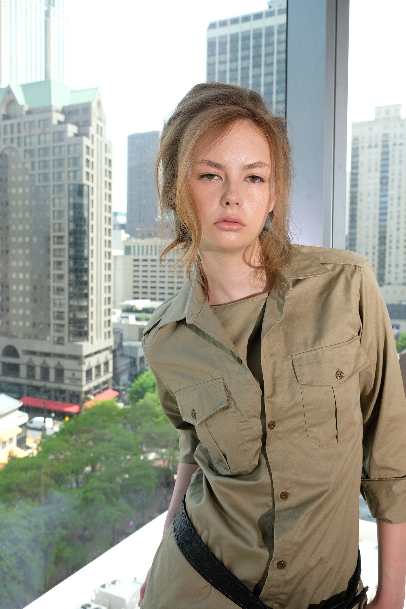 Woman in a safari shirt standing in front of a cityscape