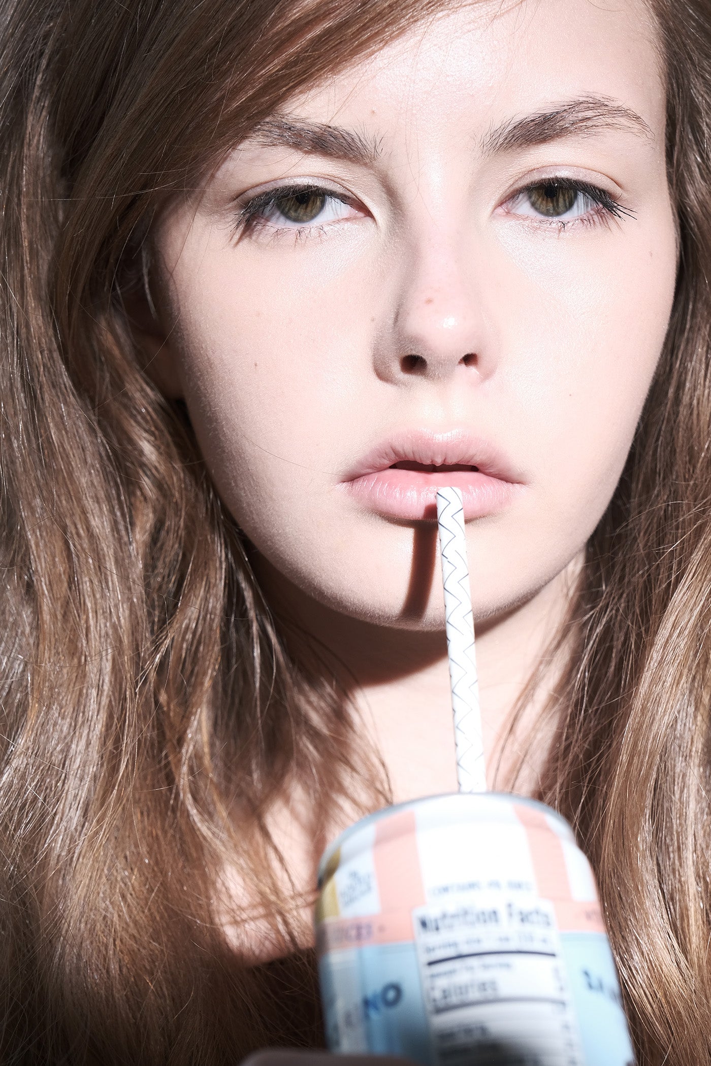 Close-up of a person holding a colorful can with a straw
